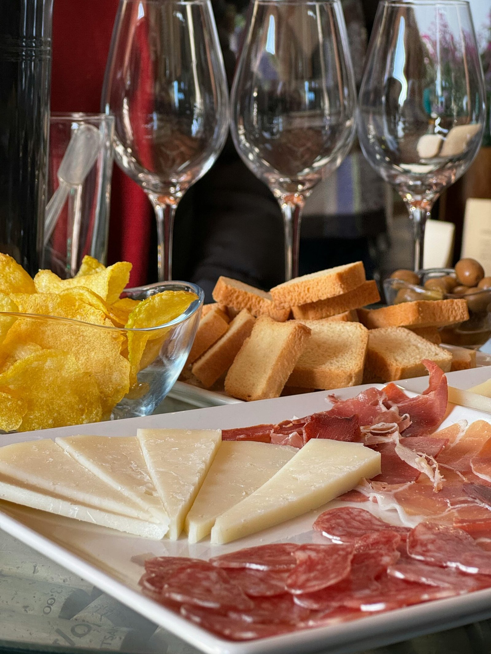 Menu A delicious spread of Spanish tapas featuring cheese, cured meats, bread, and chips, ideal for wine tasting.