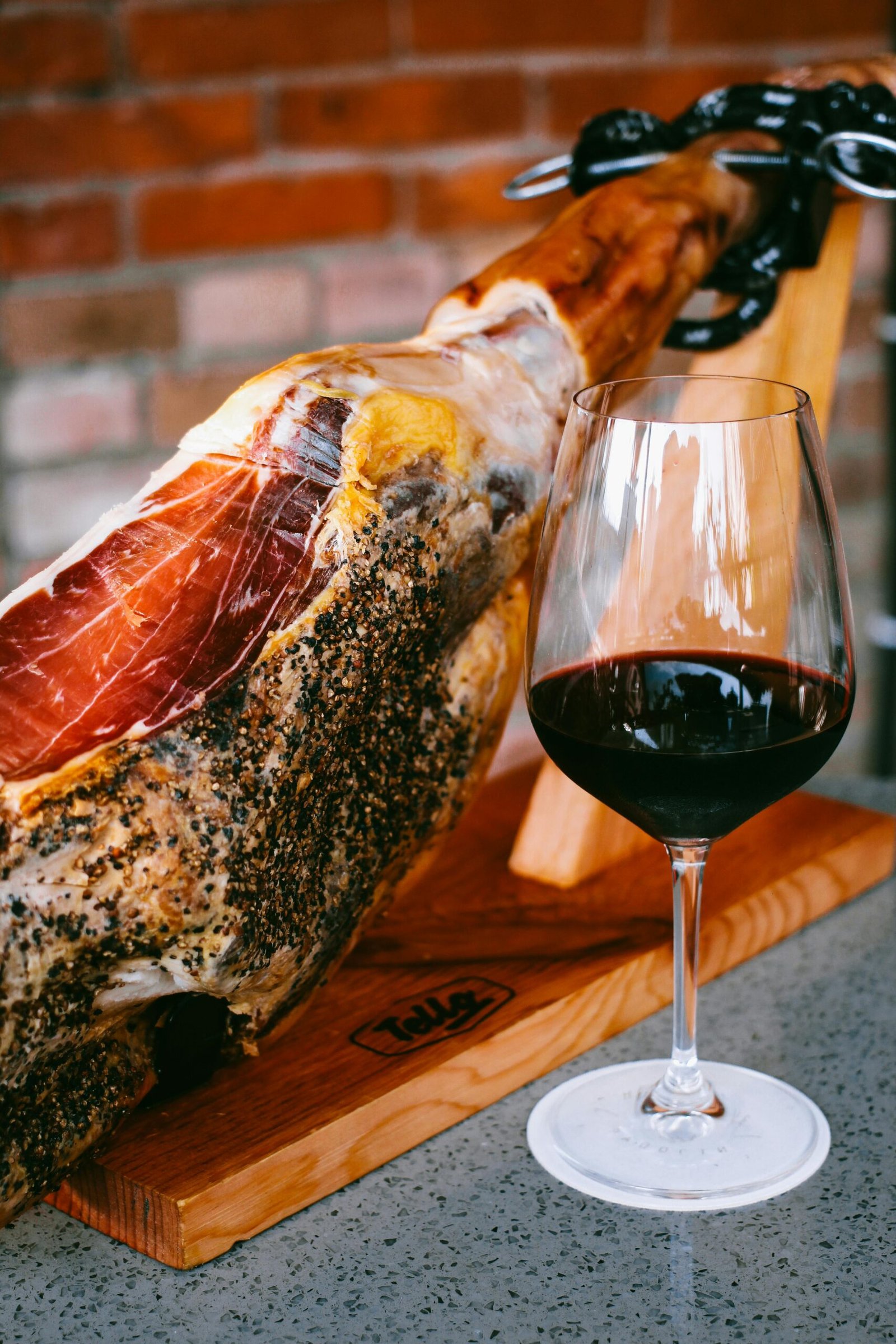 Artisan cured ham with a glass of red wine in a cozy rustic ambiance.